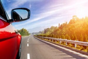 Red car driving on a scenic highway.