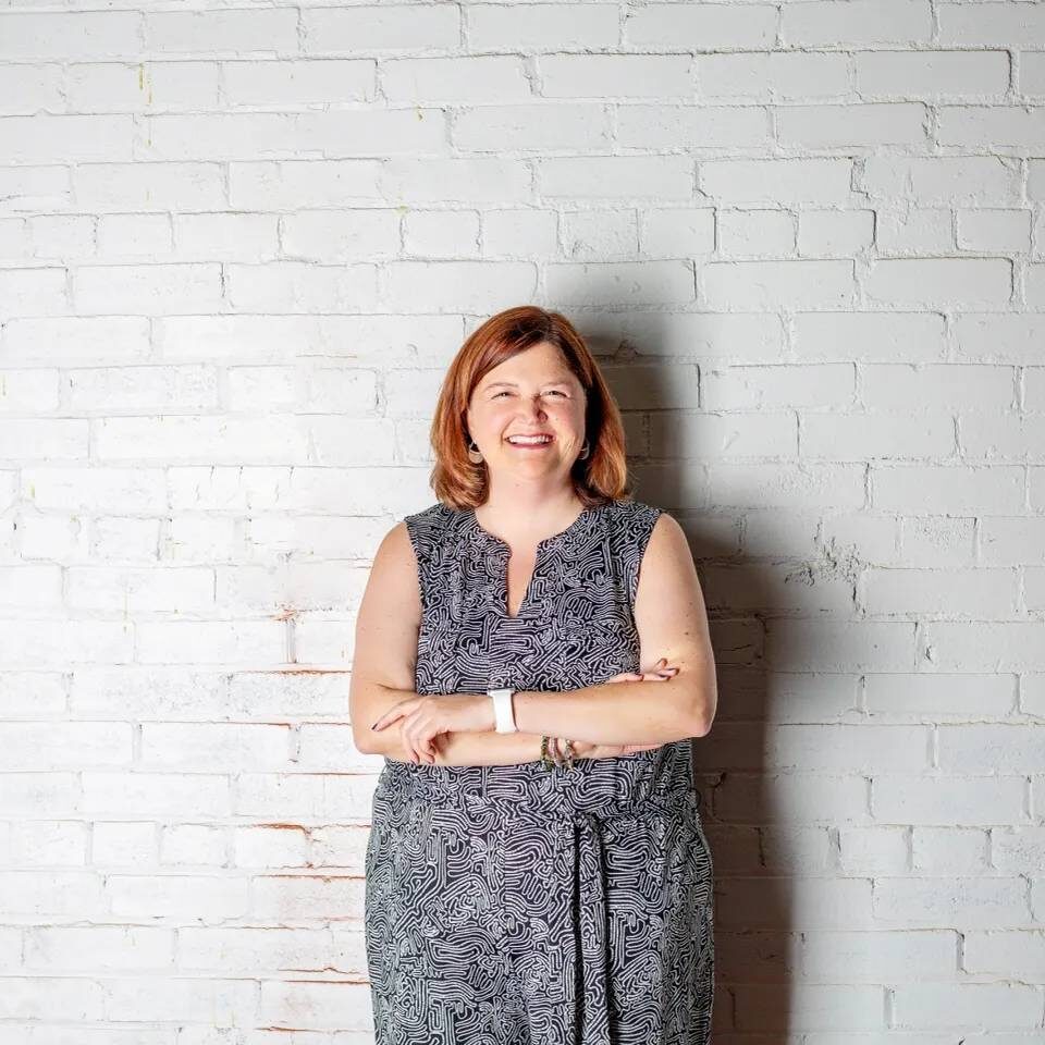 Smiling woman in a white brick wall.